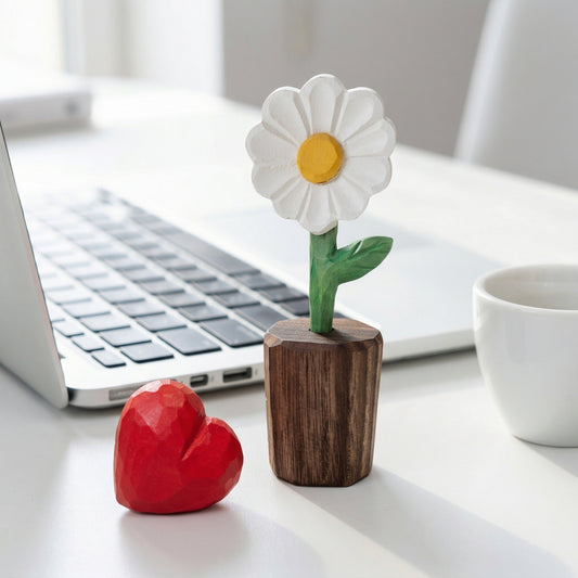 Decorative flower and heart-shaped object on a desk with a laptop in the background